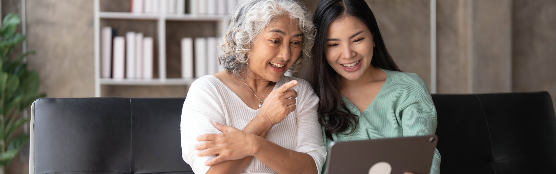 elderly woman and her caregiver using a laptop