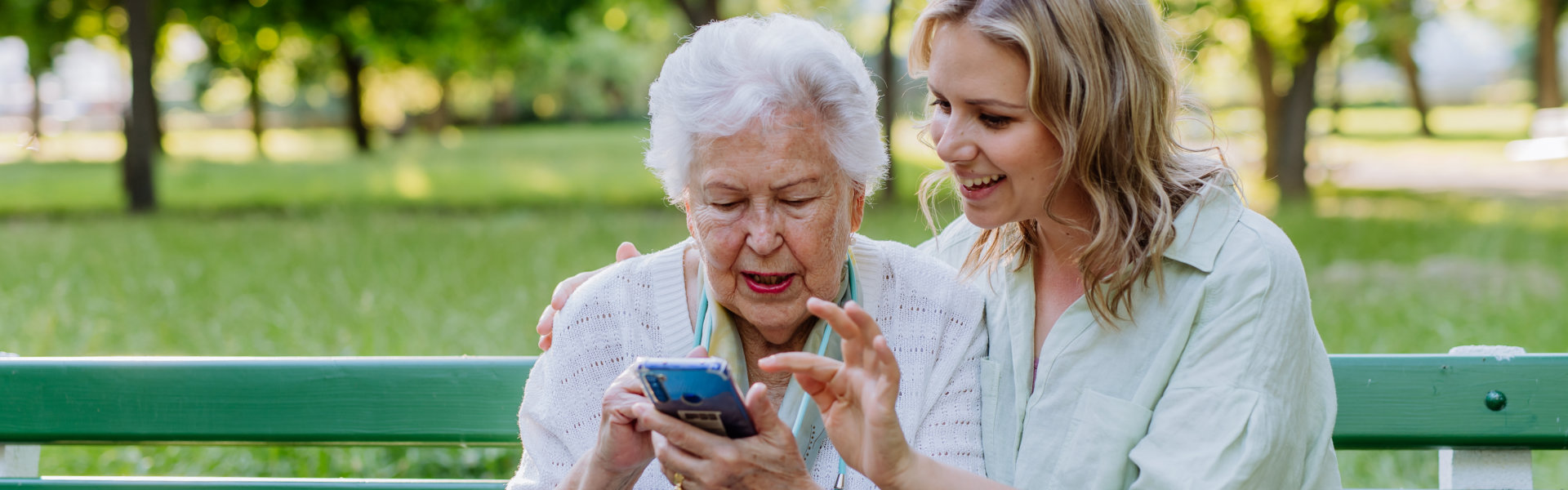 senior woman using a phone with her caregiver beside