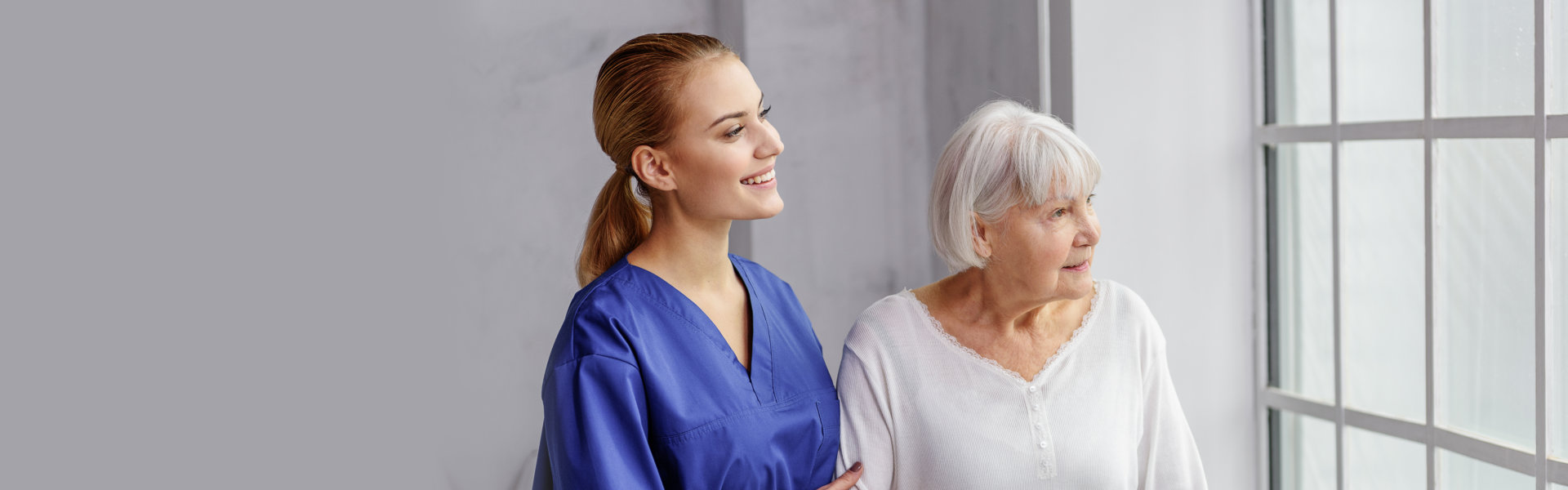 elderly woman and caregiver looking outside the window