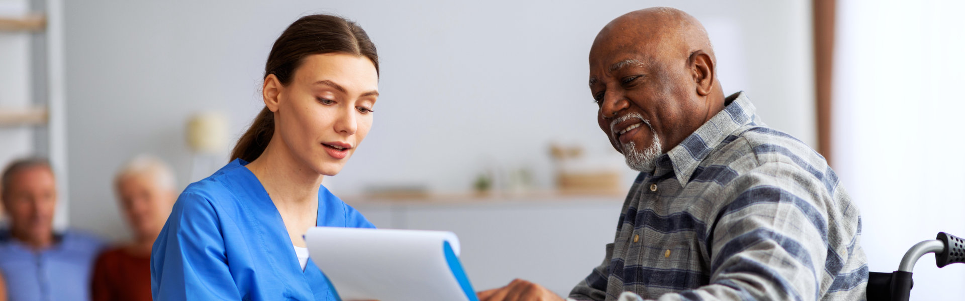 senior man and his carer reading something on a clipboard